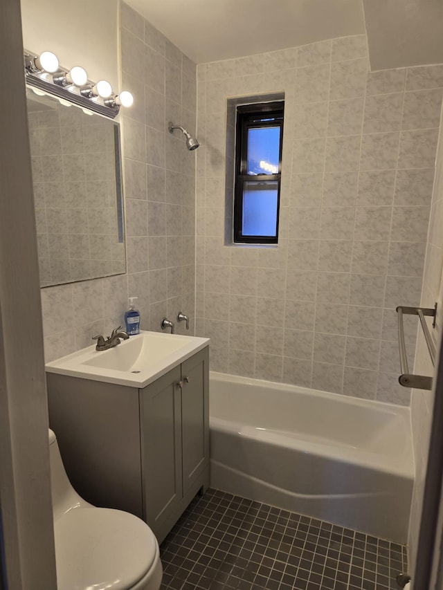 full bathroom with tiled shower / bath, tile walls, tile patterned flooring, vanity, and toilet