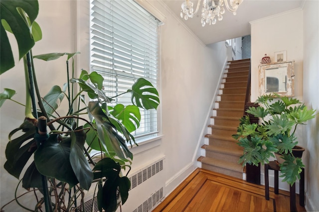 staircase featuring baseboards, ornamental molding, a chandelier, and wood finished floors