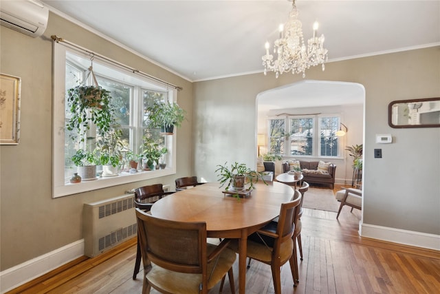 dining area featuring arched walkways, crown molding, radiator, an AC wall unit, and wood finished floors