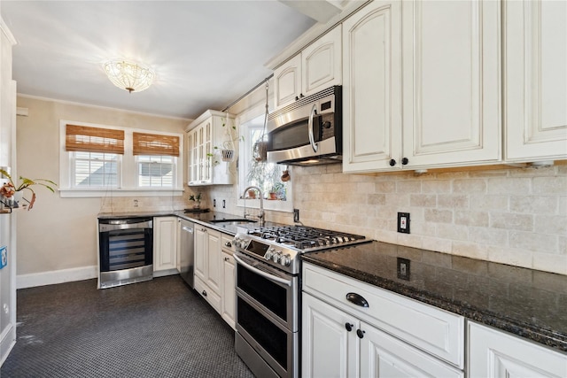 kitchen with wine cooler, a sink, appliances with stainless steel finishes, dark stone countertops, and glass insert cabinets