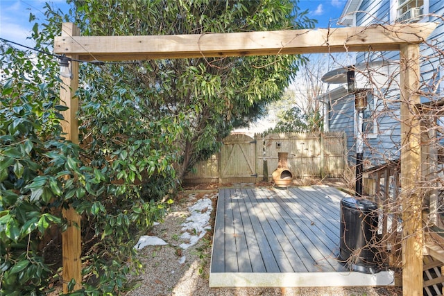 wooden terrace featuring an outdoor stone fireplace and fence