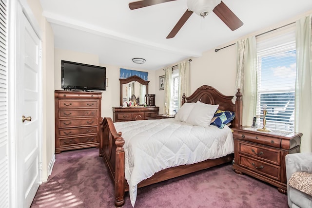 bedroom with a ceiling fan, dark carpet, and beamed ceiling