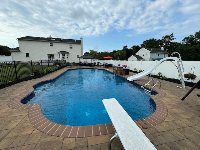 view of pool featuring a patio, a water slide, a fenced backyard, a diving board, and a fenced in pool