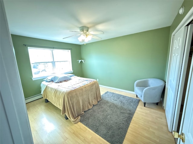 bedroom featuring baseboards, a ceiling fan, light wood-type flooring, a baseboard heating unit, and a closet