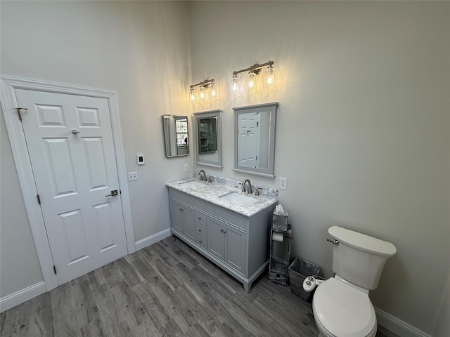 bathroom with double vanity, a sink, baseboards, and wood finished floors