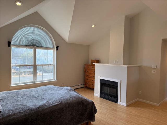 bedroom with recessed lighting, baseboard heating, a glass covered fireplace, vaulted ceiling, and light wood-type flooring