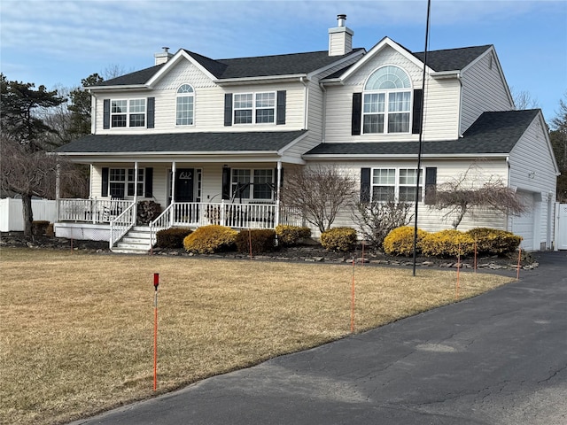 view of front of property featuring a garage, covered porch, a chimney, and a front lawn