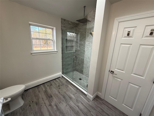 full bath with a stall shower, a baseboard radiator, baseboards, and wood finished floors