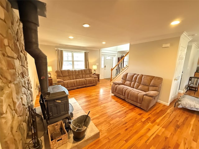 living room featuring light wood-style flooring, recessed lighting, stairway, a wood stove, and crown molding