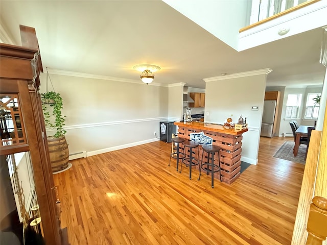 dining space featuring baseboard heating, baseboards, crown molding, and light wood finished floors