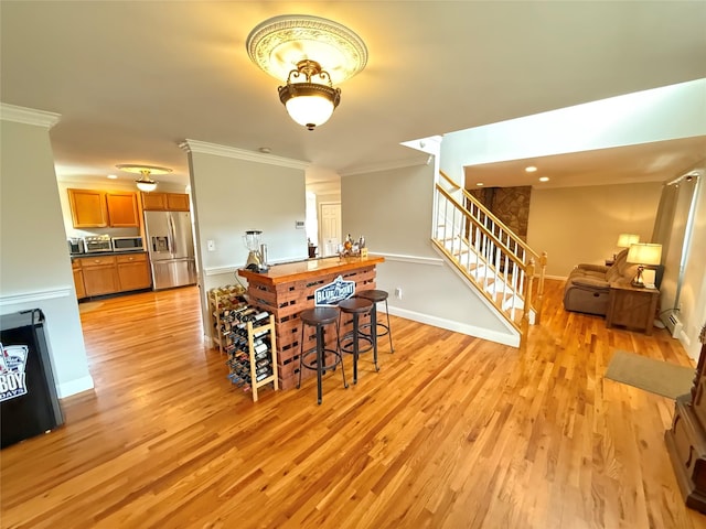 dining space featuring light wood-type flooring, baseboards, stairway, and ornamental molding