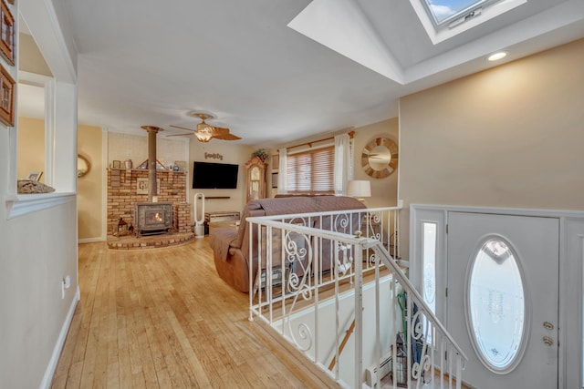 entryway featuring hardwood / wood-style flooring, a wealth of natural light, a skylight, and a wood stove