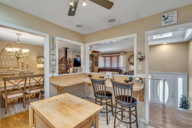 kitchen with ceiling fan with notable chandelier, light hardwood / wood-style flooring, and kitchen peninsula