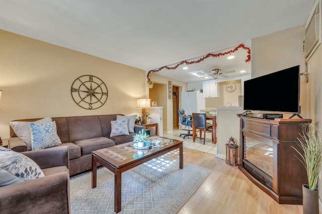 living room with ceiling fan and light hardwood / wood-style flooring