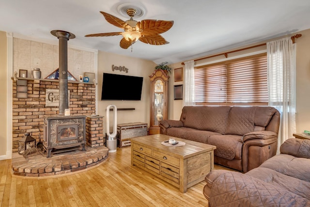 living room with ceiling fan, light hardwood / wood-style flooring, and a wood stove