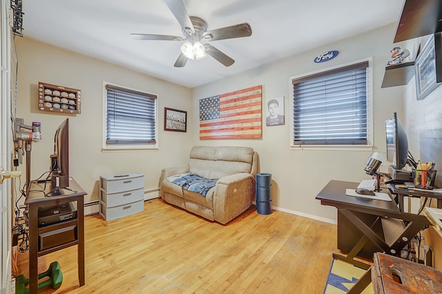 living area featuring baseboard heating, ceiling fan, a healthy amount of sunlight, and light hardwood / wood-style floors