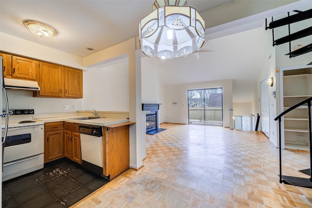 kitchen featuring white appliances, light parquet flooring, sink, and a high ceiling