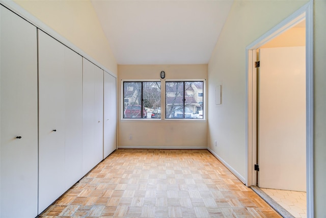 unfurnished bedroom with vaulted ceiling, a closet, and light parquet floors