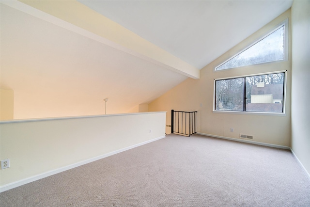 additional living space featuring lofted ceiling with beams and light carpet