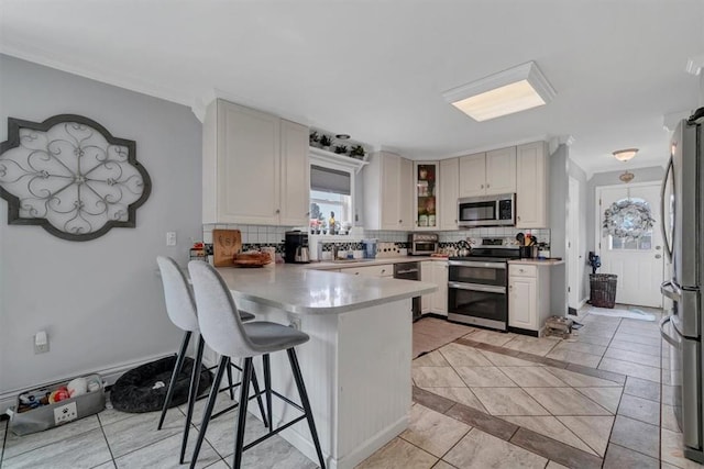 kitchen with light tile patterned flooring, a breakfast bar, tasteful backsplash, appliances with stainless steel finishes, and kitchen peninsula