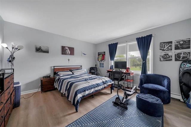 bedroom with baseboard heating and light hardwood / wood-style flooring