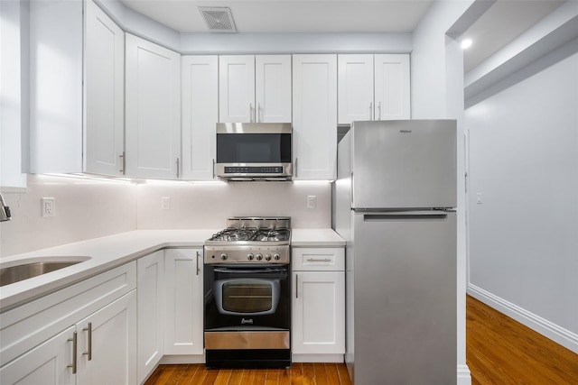 kitchen featuring stainless steel appliances, sink, light wood-type flooring, and white cabinets