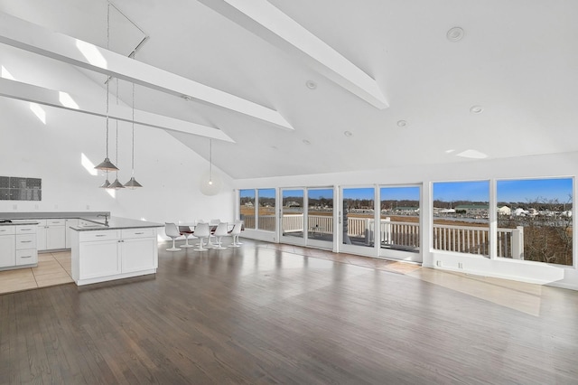 unfurnished living room with beam ceiling, high vaulted ceiling, and hardwood / wood-style flooring