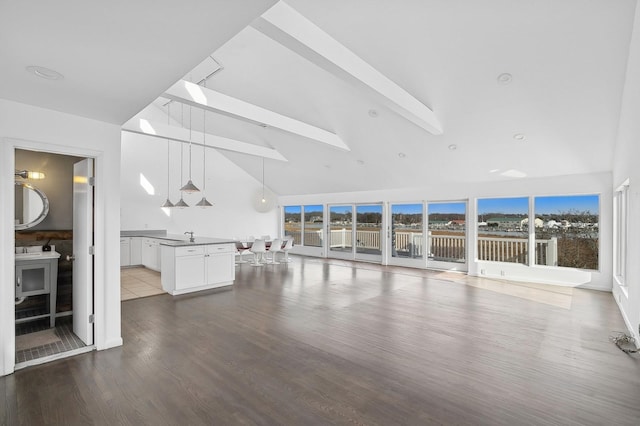 unfurnished living room with hardwood / wood-style floors, beam ceiling, a skylight, and high vaulted ceiling