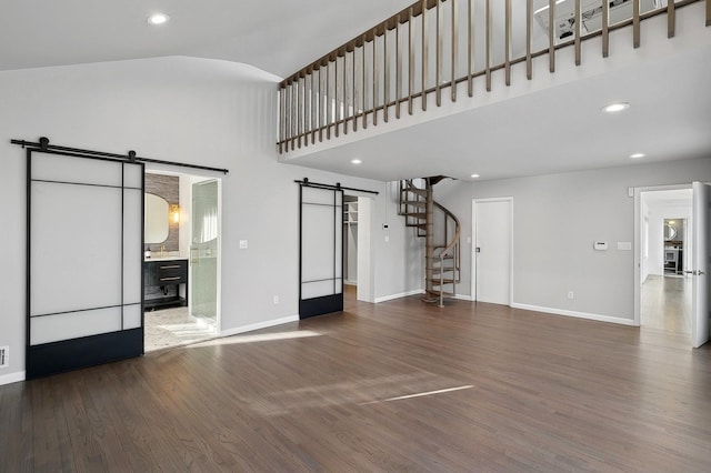 unfurnished living room with a high ceiling, a barn door, and dark hardwood / wood-style floors