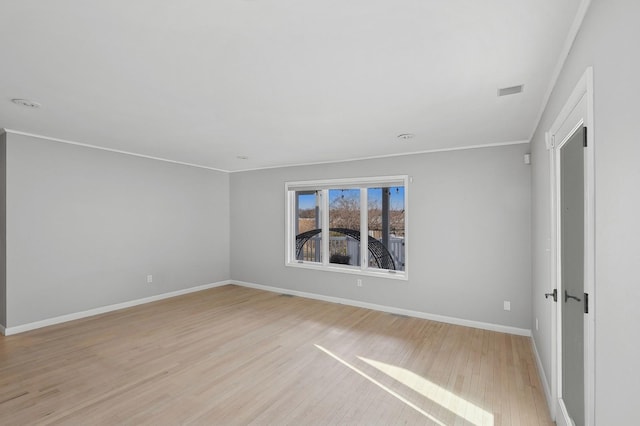 spare room featuring crown molding and light hardwood / wood-style floors