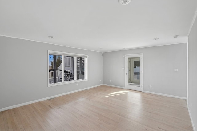 empty room with crown molding and light hardwood / wood-style floors