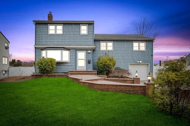 back house at dusk featuring a yard and a garage