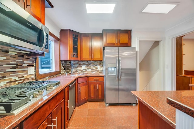 kitchen with appliances with stainless steel finishes, light stone countertops, sink, and backsplash