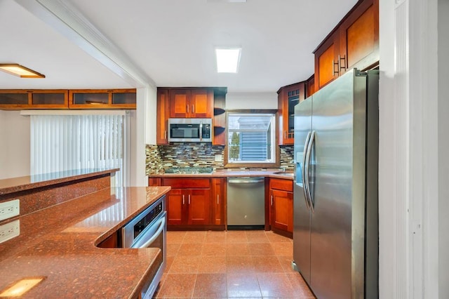 kitchen featuring appliances with stainless steel finishes, dark stone countertops, and decorative backsplash