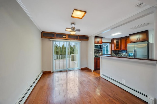 kitchen featuring ornamental molding, a baseboard radiator, stainless steel appliances, and light hardwood / wood-style floors