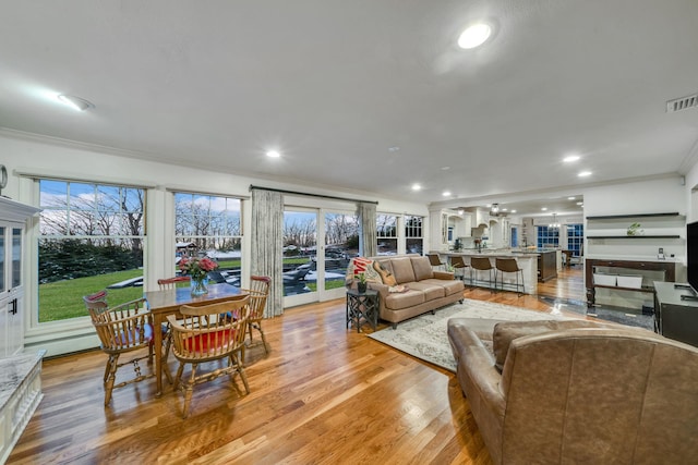 living room with ornamental molding, light hardwood / wood-style floors, and a healthy amount of sunlight