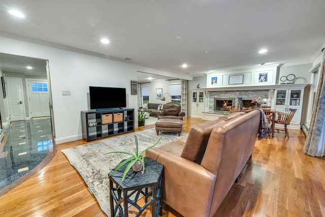 living room featuring ornamental molding, a high end fireplace, and light wood-type flooring