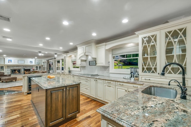 kitchen with sink, light stone counters, a center island, black electric cooktop, and beverage cooler