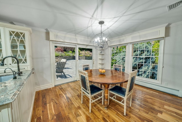 dining area with a baseboard heating unit, ornamental molding, sink, and light hardwood / wood-style flooring