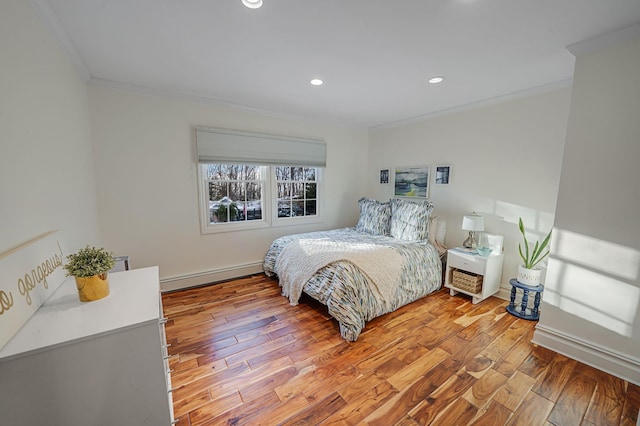 bedroom featuring ornamental molding, baseboard heating, and light hardwood / wood-style flooring