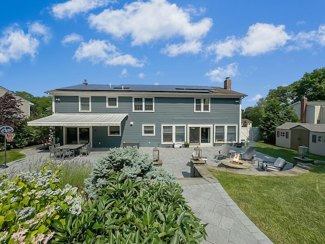 back of house featuring a patio area, a storage unit, and an outdoor fire pit