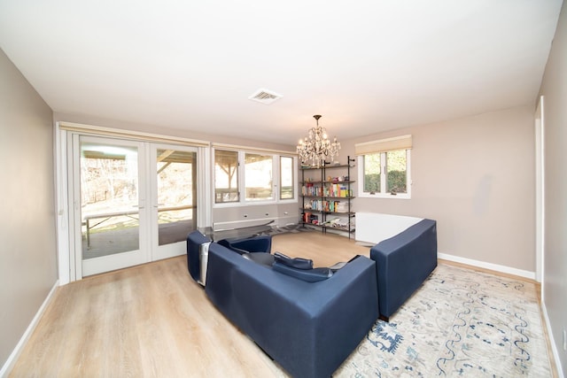 living room featuring an inviting chandelier, french doors, and light wood-type flooring