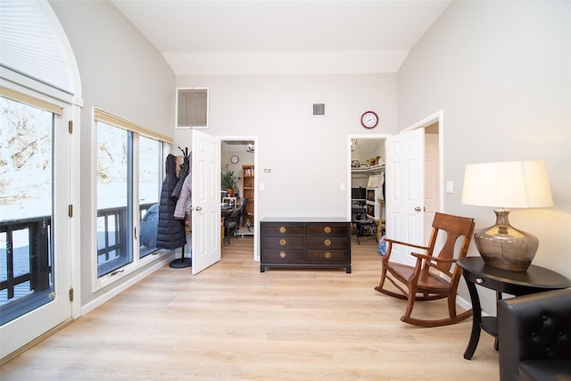 living area with high vaulted ceiling and light hardwood / wood-style floors