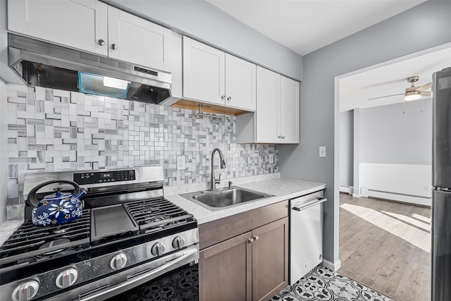 kitchen with white cabinetry, a baseboard radiator, sink, ceiling fan, and stainless steel appliances