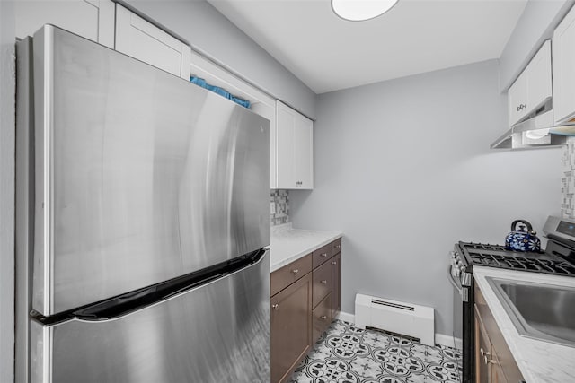 kitchen with light tile patterned floors, sink, appliances with stainless steel finishes, white cabinetry, and a baseboard radiator