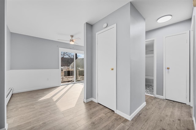 hall with light hardwood / wood-style floors and a baseboard heating unit