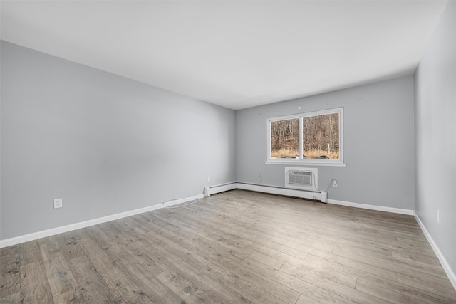 spare room with a baseboard radiator, an AC wall unit, and light wood-type flooring