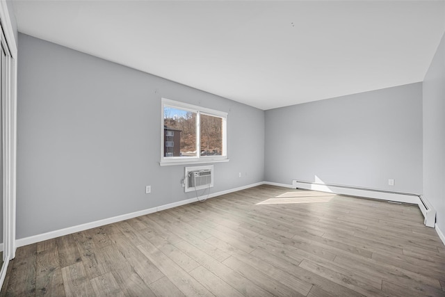 unfurnished room with a baseboard heating unit, light hardwood / wood-style floors, and an AC wall unit