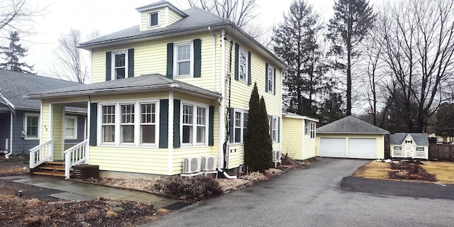 view of home's exterior featuring a shingled roof, entry steps, an outdoor structure, and a detached garage