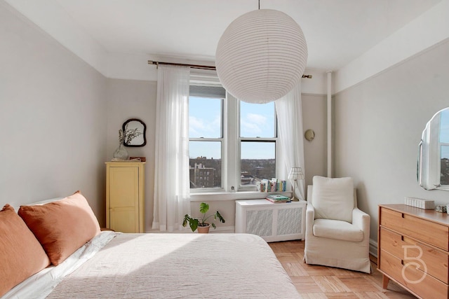 bedroom with light parquet floors and radiator heating unit